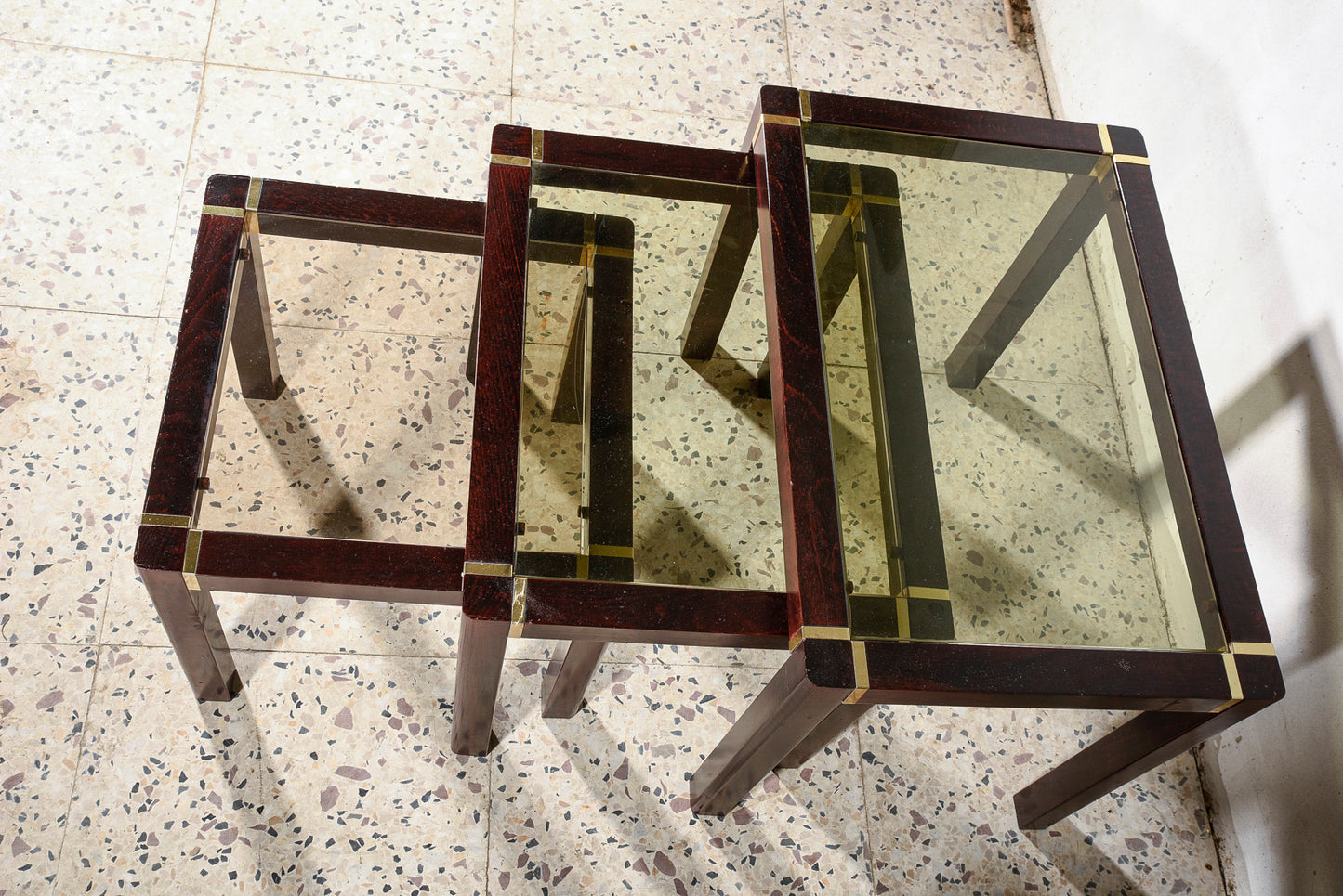 Trittico di tre tavolini impellicciati con piano in vetro e rifiniture in ottone Italia 1980