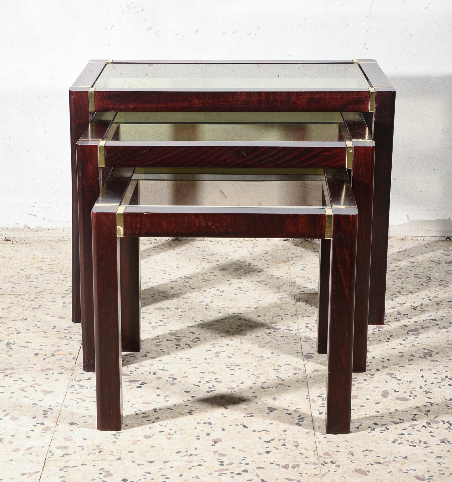 Trittico di tre tavolini impellicciati con piano in vetro e rifiniture in ottone Italia 1980